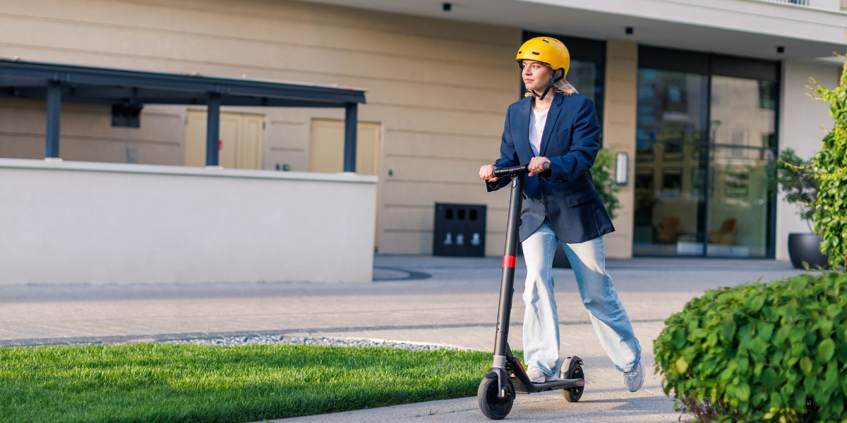 Nastolatka w kasku podczas jazdy na hulajnodze elektrycznej